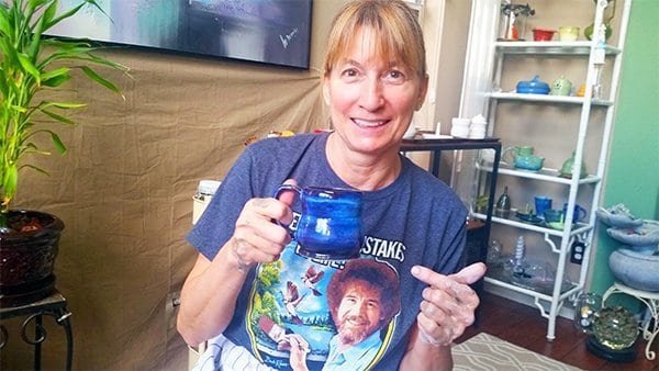 a picture of a potter pointing at a blue mug