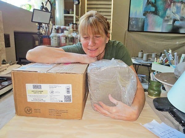 a picture of a potter hugging a premixed moist bag of pottery clay