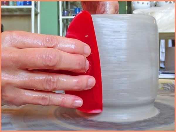 a picture of a potter using a large red rib