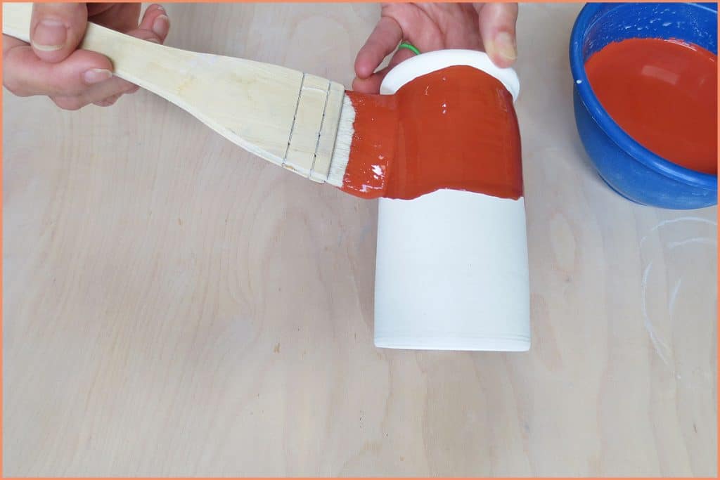 a picture of a potter glazing with a hack brush