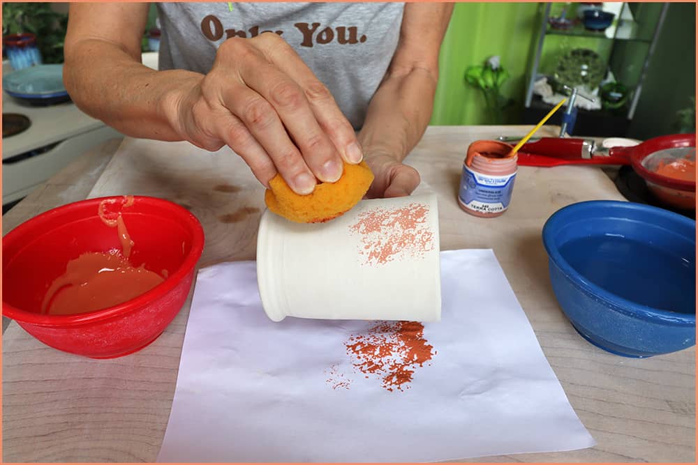 a picture of a potter appying underglaze with sponge