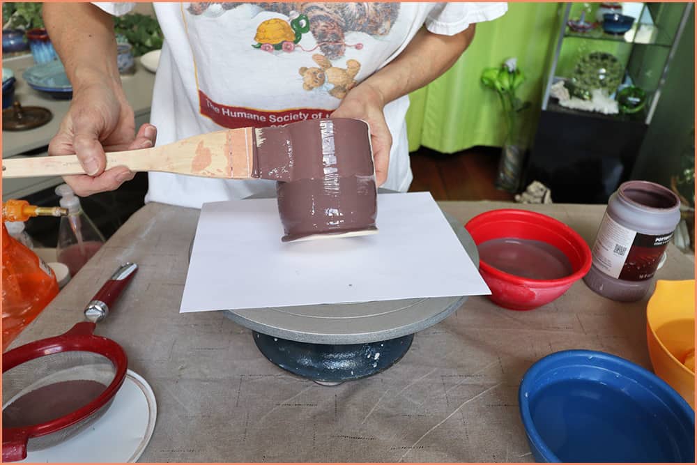 a picture of brushing glaze on a mug