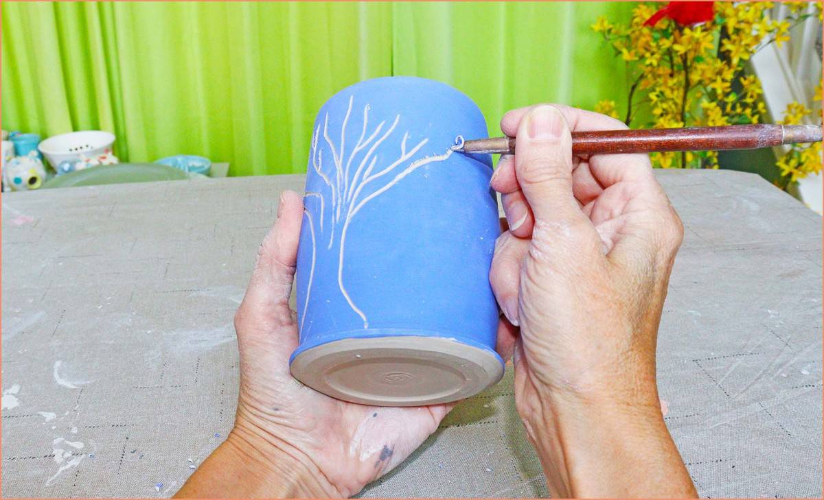 a picture of a potter carving underglaze greenwear