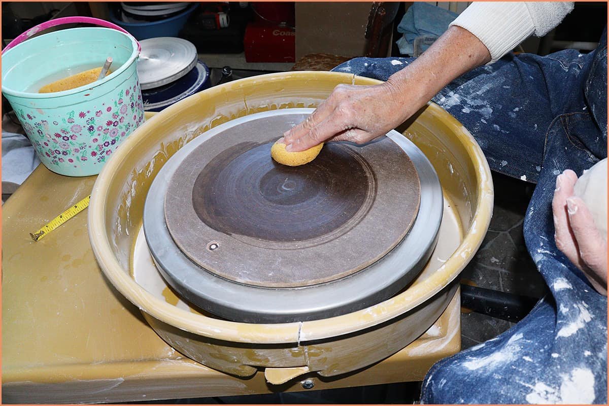 an image of a potter wiping the Bat using a damp sponge