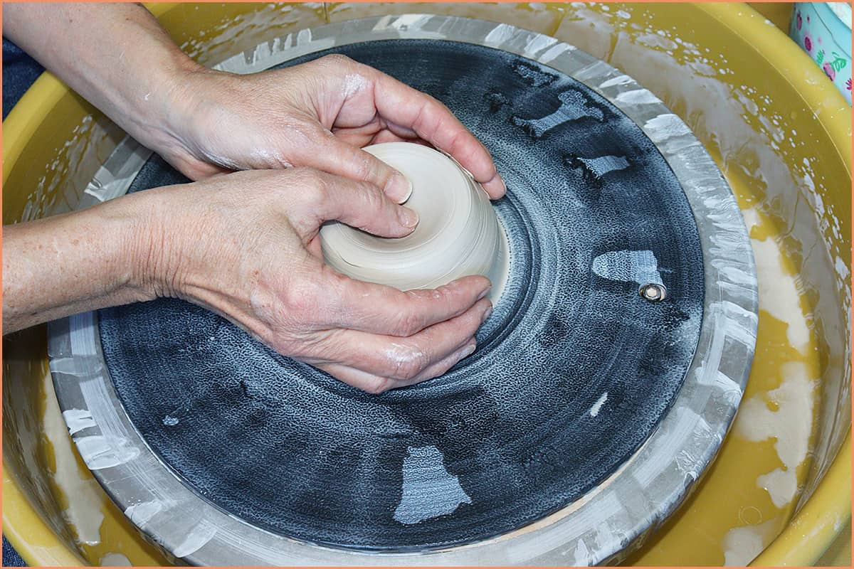 an image of a potter opening clay with thumbs