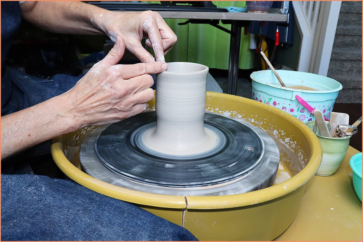 an image of a potter compressing the rim