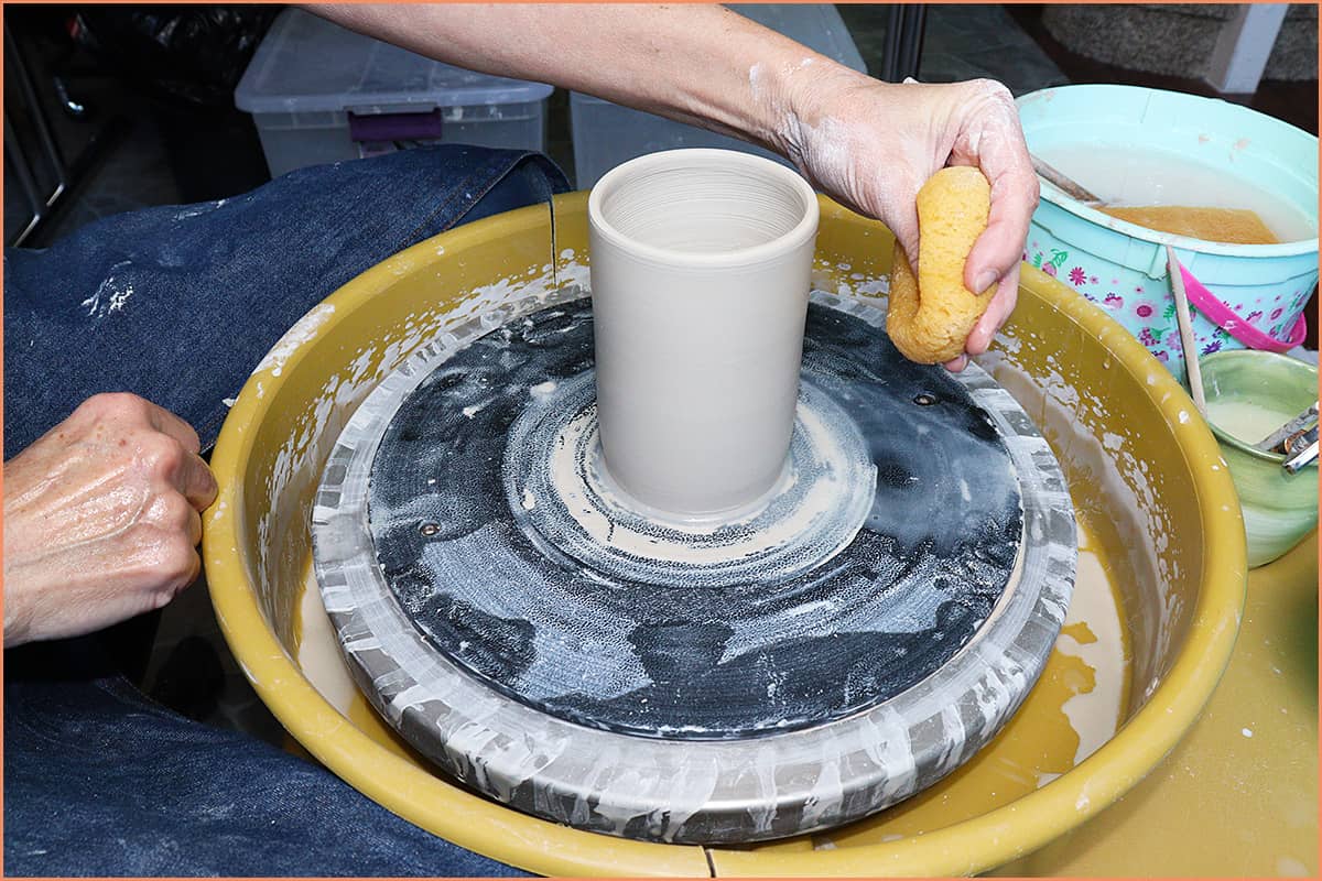 an image of a potter putting water on the wheel