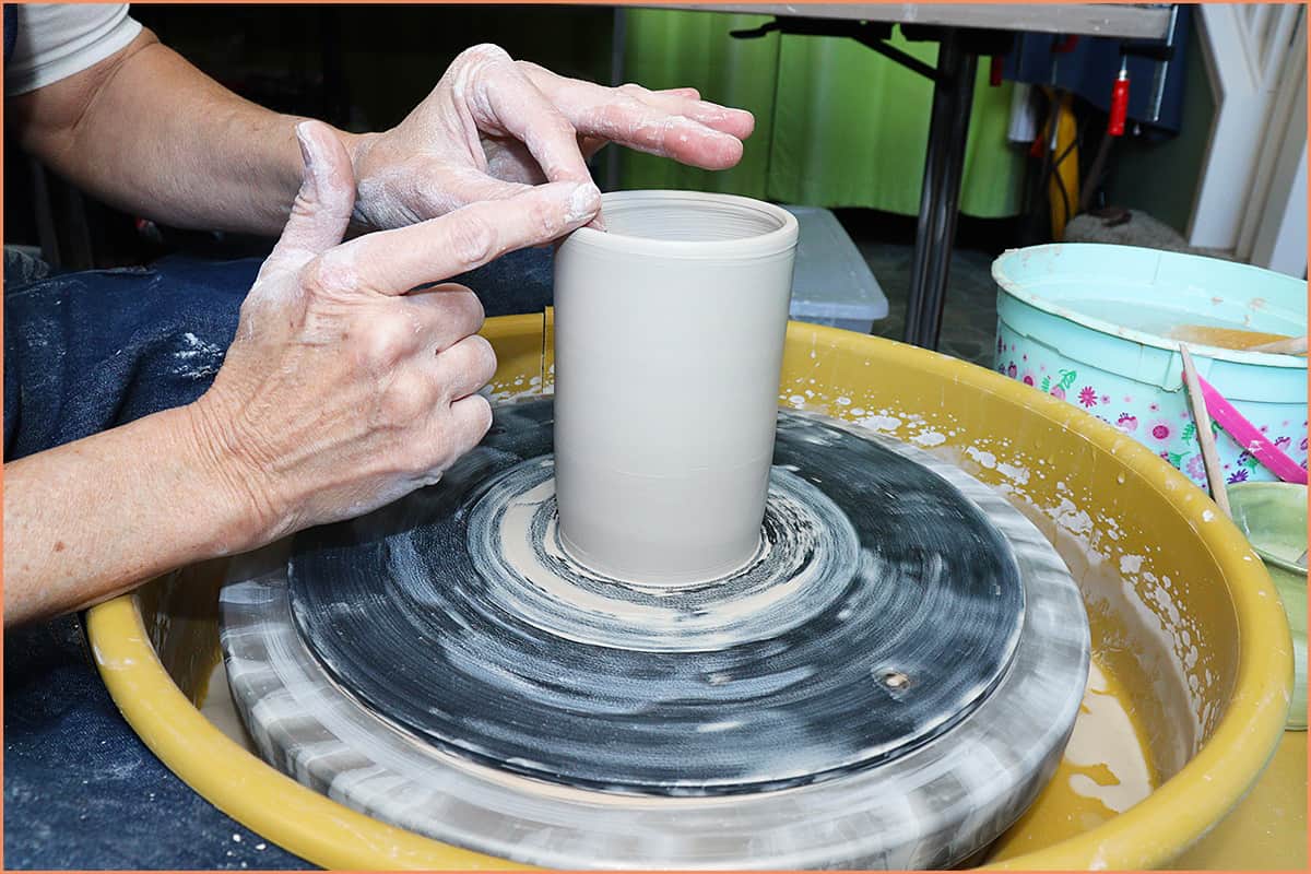 an image of a potter smoothing out the rim