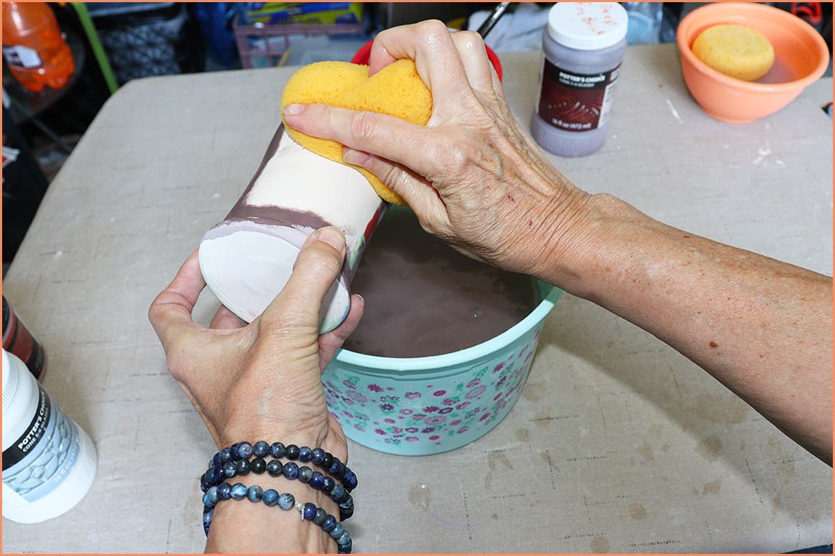 an image of a potter removing all the glaze with a sponge