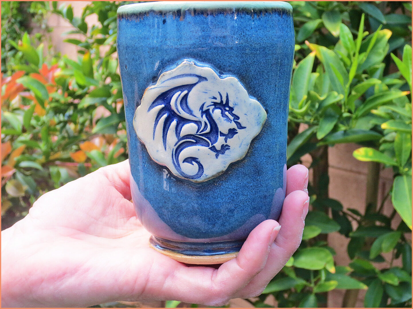 an image of potter holding a dragon stamped into a mug 